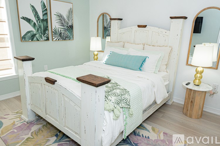 A white bed with a wooden headboard and footboard with a green throw pillow on it.