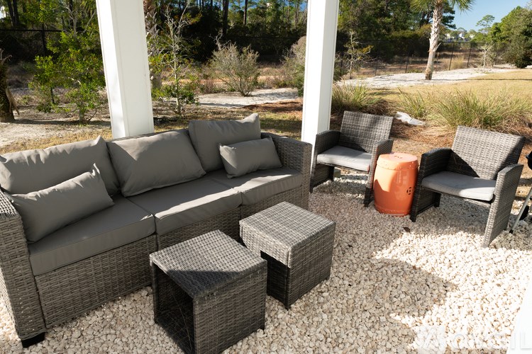 A grey outdoor sofa set with pillows and a wicker coffee table.