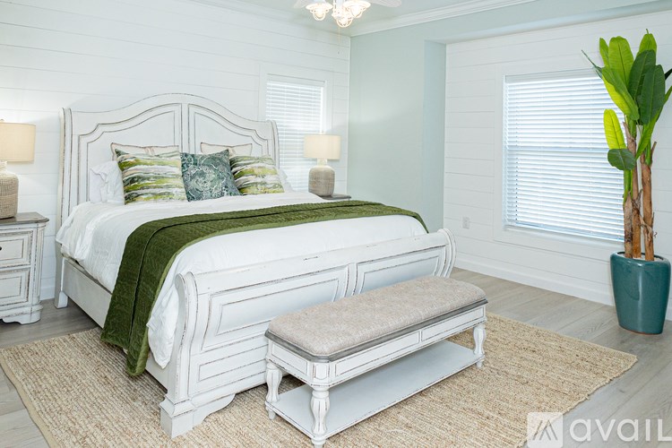 A white bedroom with a large bed and a bench.