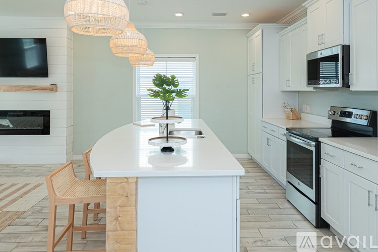 A modern kitchen with a white island and wooden chairs.