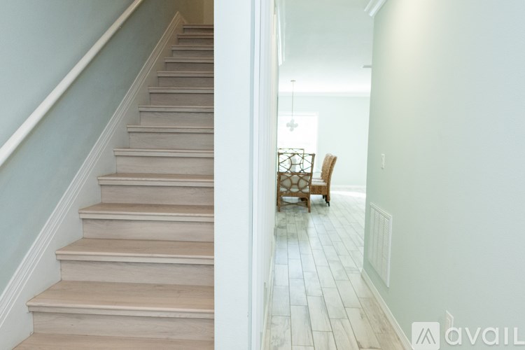 A staircase with a wooden banister and a chair in the background.