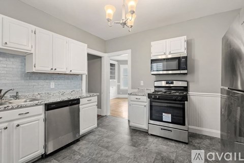 A kitchen with white cabinets and a marble countertop.