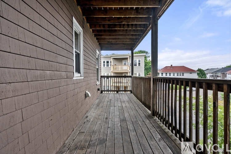 A wooden deck with a railing and a window overlooks a residential area.