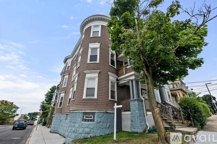 A multi-story building with a blue trim and a tree in front.