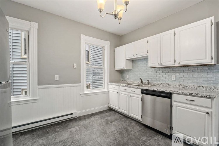 A kitchen with white cabinets and a brick backsplash.