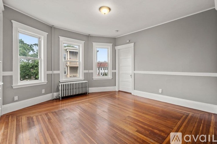 A room with wooden floors and three windows.