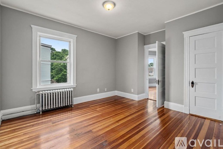 A room with wooden floors and a window with a view of trees.
