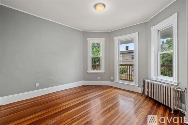 A room with wooden floors and three windows.