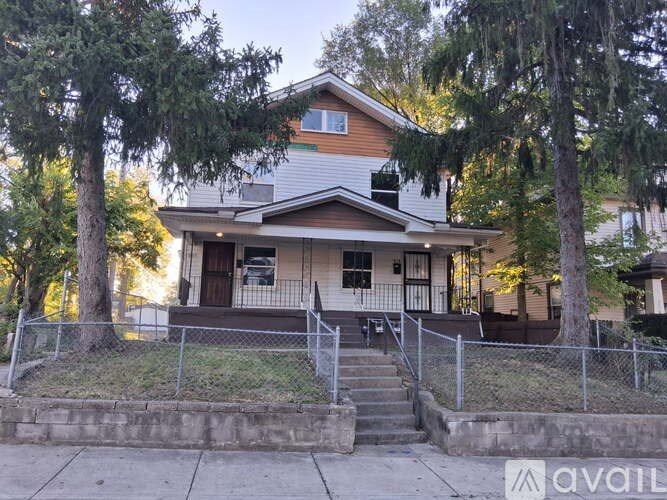 A house with a front porch and a tree in front.