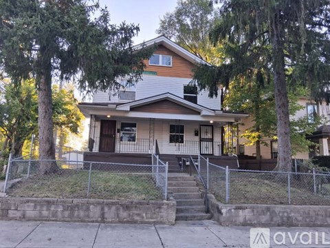 A house with a front porch and a tree in front.