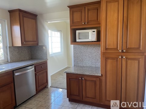 A kitchen with wooden cabinets and a stainless steel dishwasher.