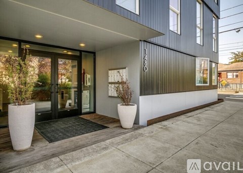 The front of a modern building with a glass door and two large planters.