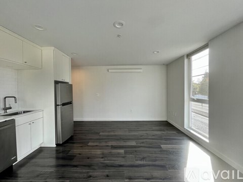 A kitchen with white cabinets and a black fridge.