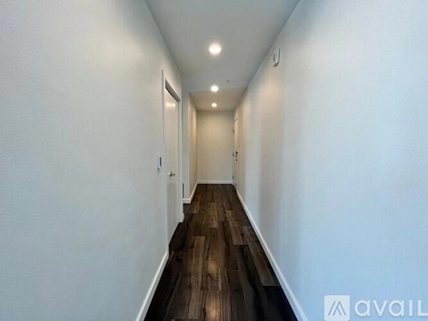 A long hallway with wooden floors and white walls.