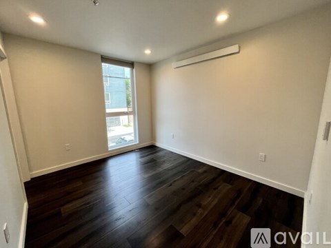 A spacious room with wooden floors and a window.