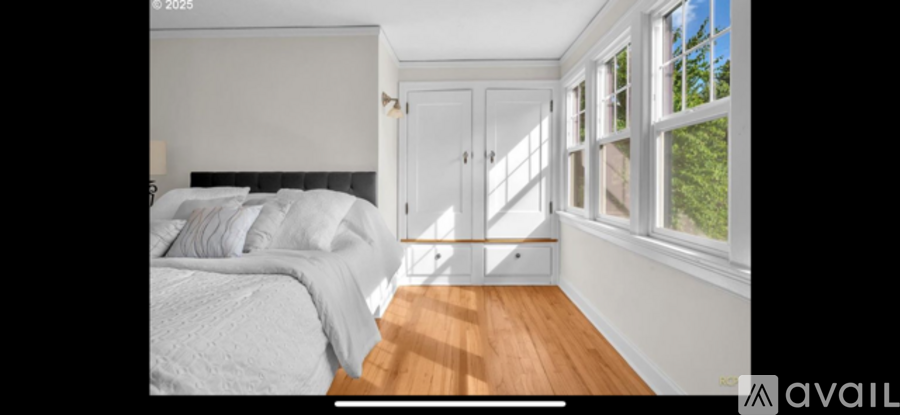 A bedroom with a large bed and a window with a view of trees.