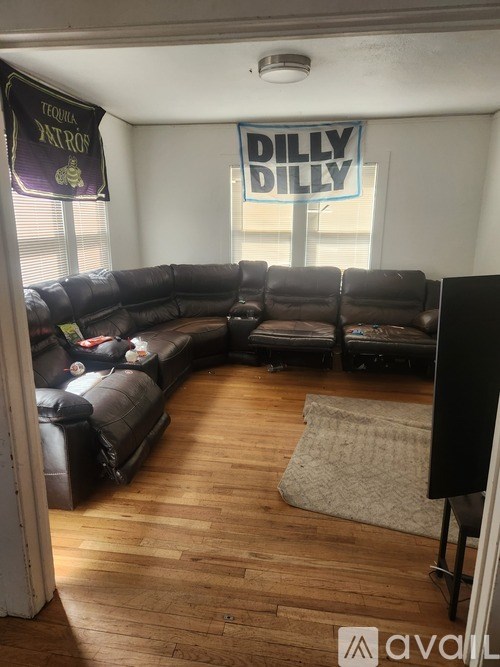 A living room with a black couch and a rug on the floor.
