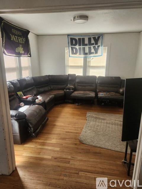 A living room with a black couch and a rug on the floor.