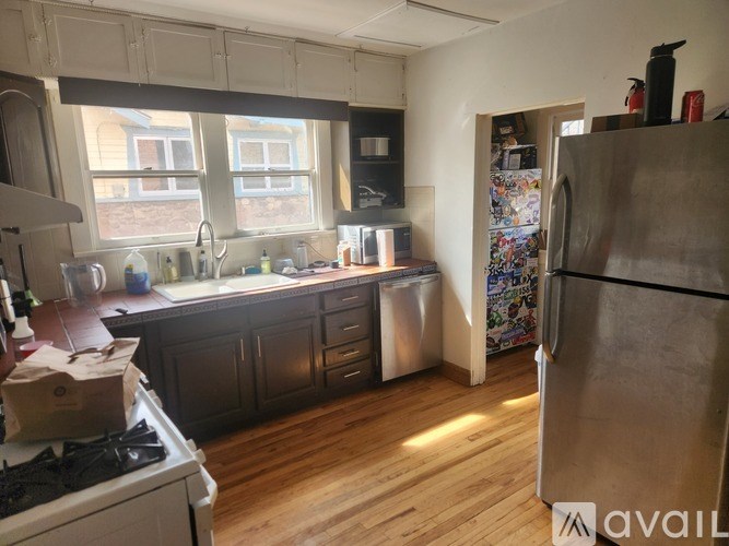 A kitchen with wooden floors and a refrigerator on the right.