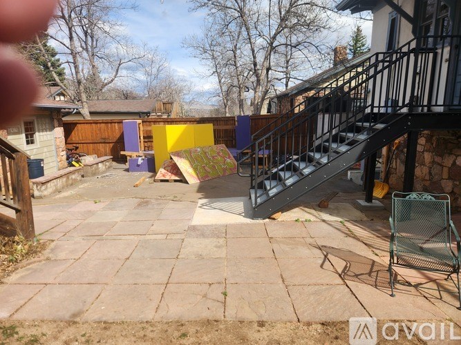 A backyard with a patio, a chair, and a staircase.
