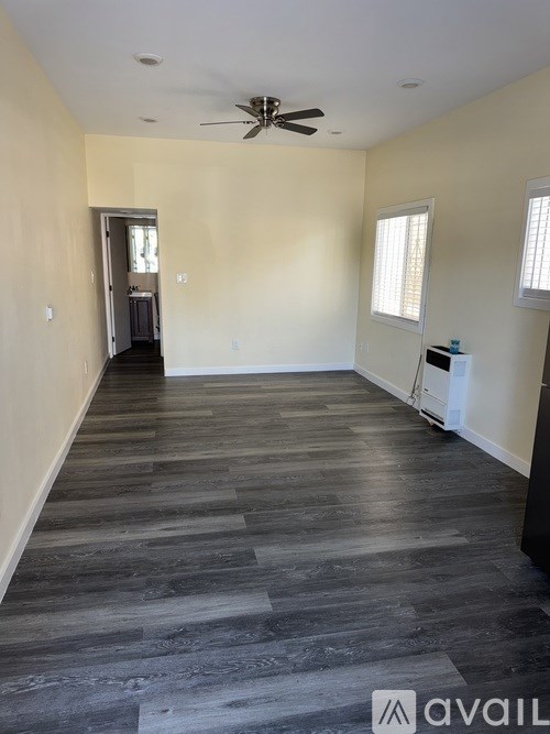 A spacious room with a ceiling fan and wood flooring.