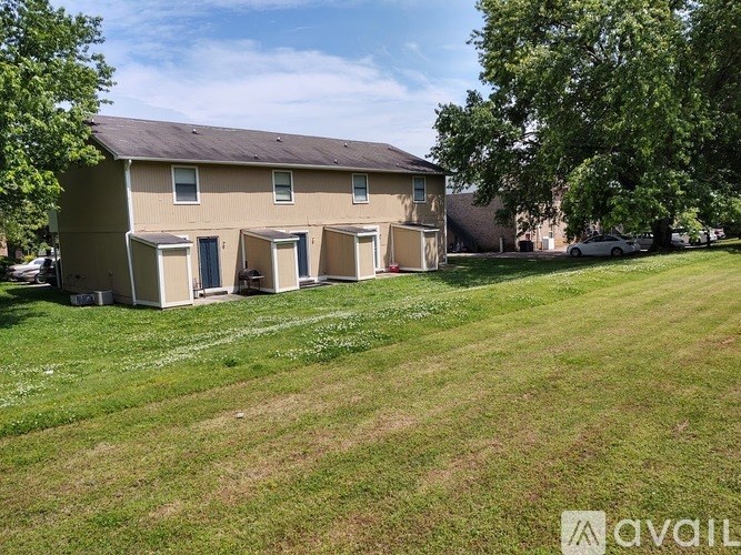 A beige house with a brown roof and a white car parked in front.
