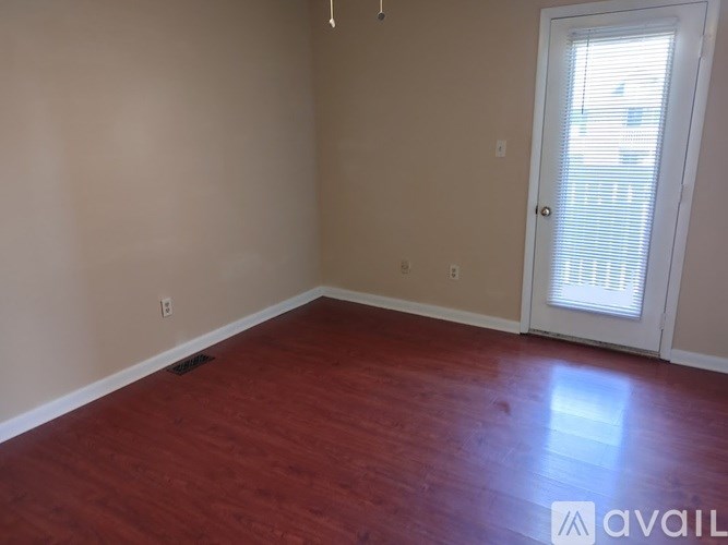 A room with a wooden floor and a door leading to a balcony.