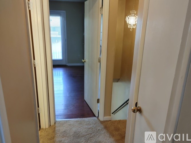 A hallway with a rug and a chandelier.