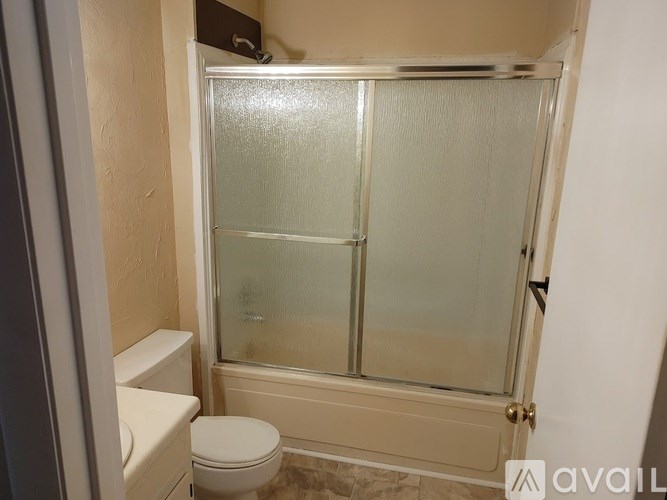 A bathroom with a toilet, a glass shower door, and a tiled floor.