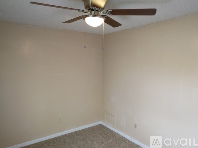 A room with a ceiling fan and carpeted floor.