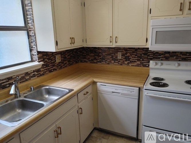 A kitchen with a stove, sink, and cabinets.