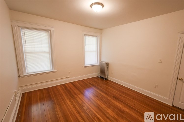 A room with wooden floors and two windows.