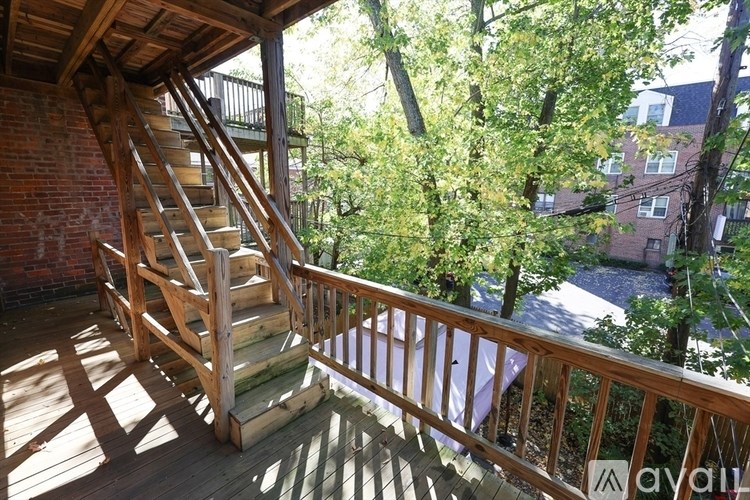 A wooden staircase on a balcony with trees in the background.
