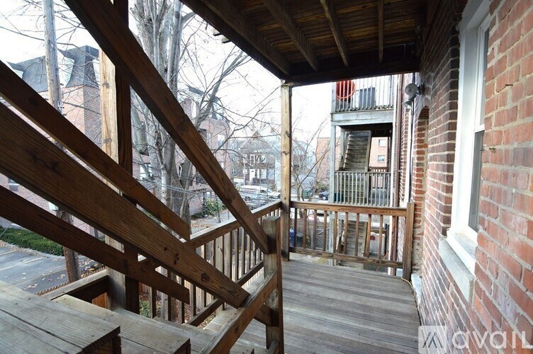 A wooden deck with a railing and steps leading up to a balcony.