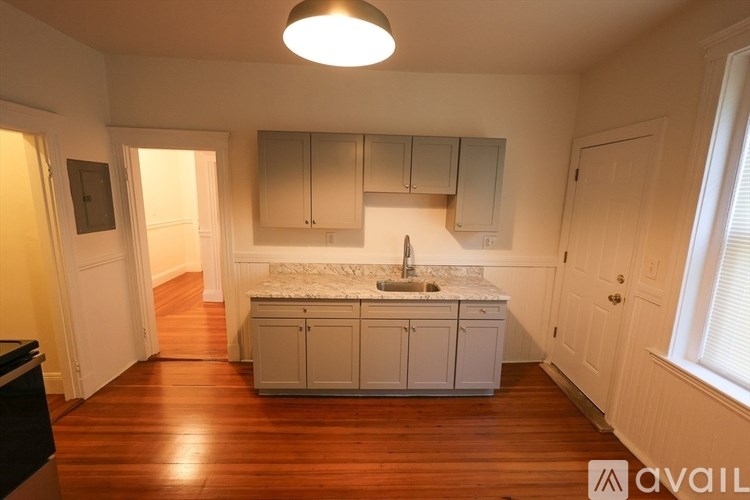 A kitchen with wooden floors and white cabinets.