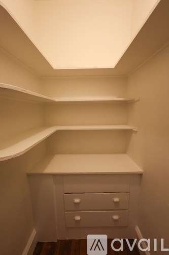 A white cabinet with two drawers is under a skylight.