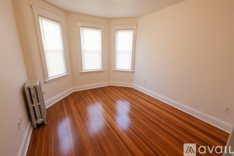 A room with wooden floors and three windows.