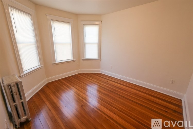 A room with wooden floors and three windows.