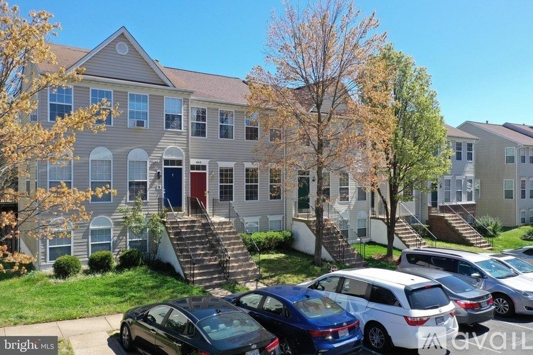 A row of houses with cars parked in front.