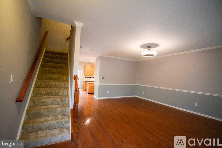 A room with wooden floors and a staircase leading to another room.