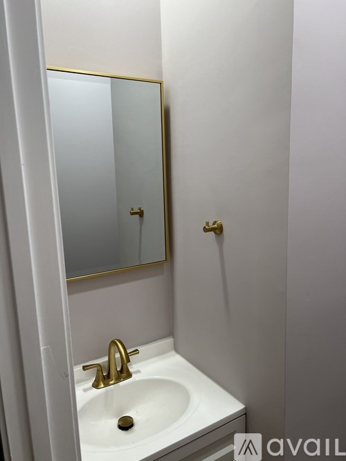 A white sink with a gold faucet and a mirror above it.