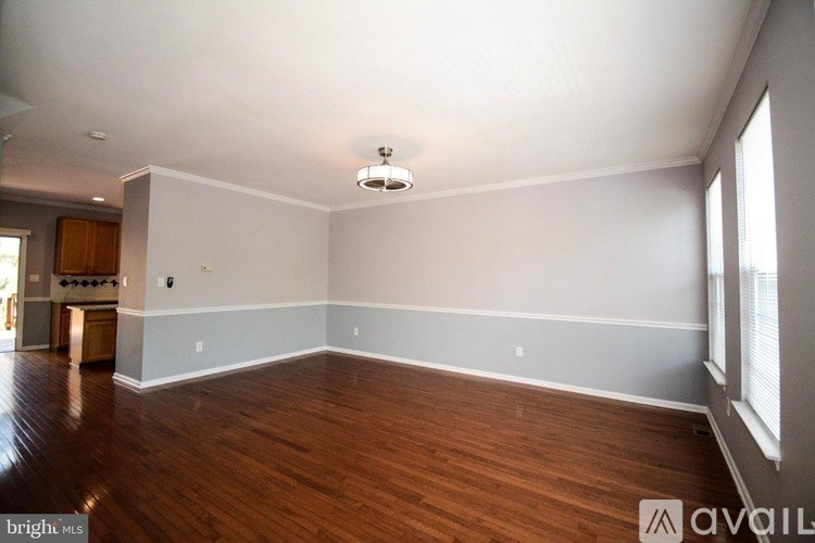 A spacious room with wooden floors and a large window.