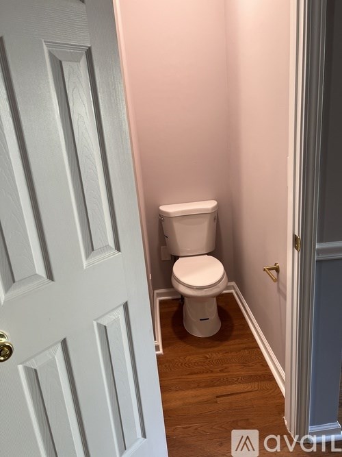 A white toilet sits in a small bathroom next to a white door.
