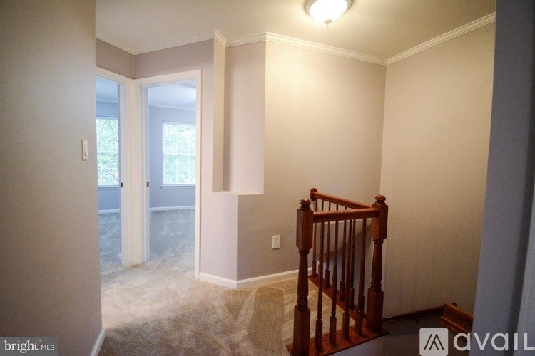 A room with a carpeted floor and a wooden staircase.