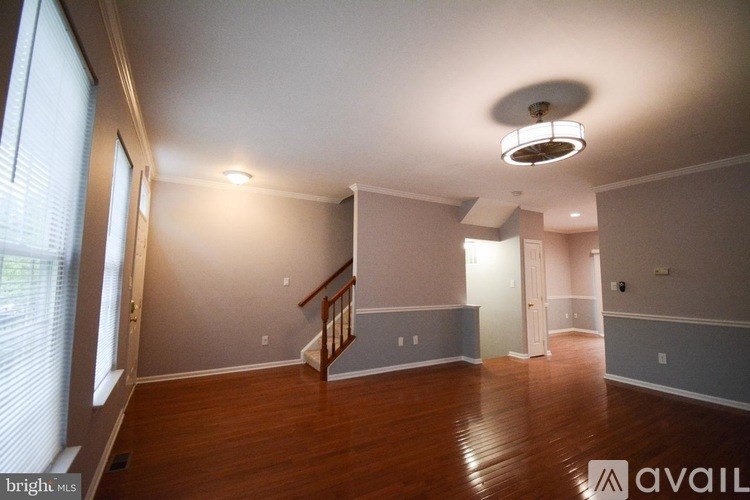 A spacious room with wooden floors and a staircase.