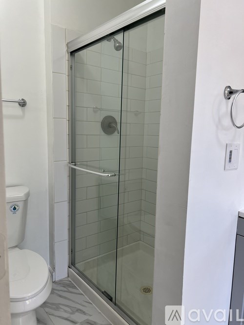 A white toilet is next to a glass shower door.
