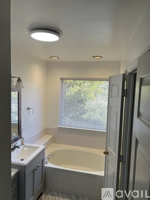 A bathroom with a tub, sink, and window.