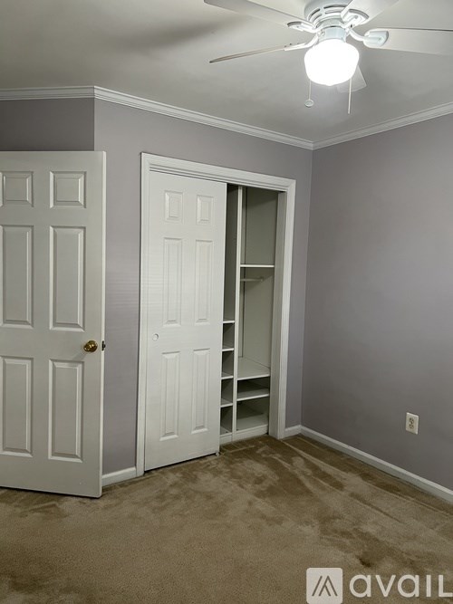 A room with a white door and a ceiling fan.