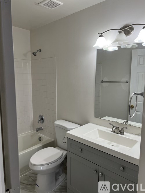 A bathroom with a toilet, sink, and mirror.