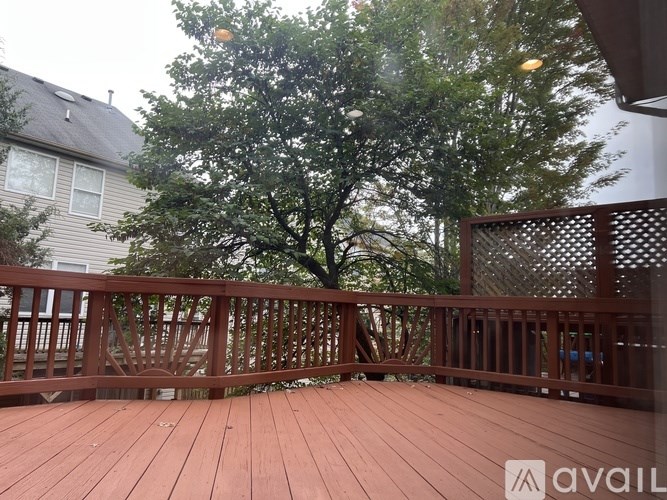 A wooden deck with a lattice fence and a tree in the background.